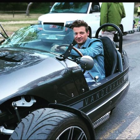 Jeremy Renner posing for a picture while driving a car